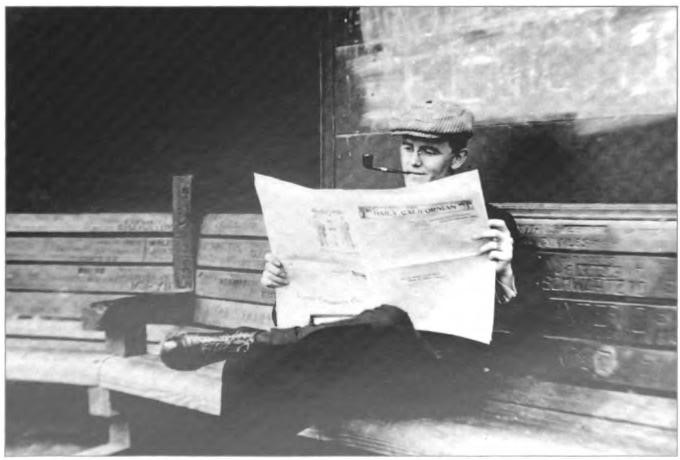 Roy Shurtleff at U.C. Berkeley, reading the Daily Californian, wearing a driving cap, and smoking a pipe, circa 1911. He later would put himself through college as the paper's business manager.