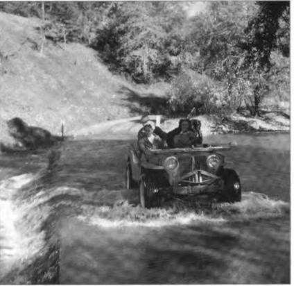 Bobbie driving her bright red World War II Jeep fording the creek at Chalk Hill Ranch.