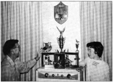 Lawton and Linda admire Carlos, Linda's favorite racer, perched among the many pigeon-racing trophies, Lafayette, circa 1955.